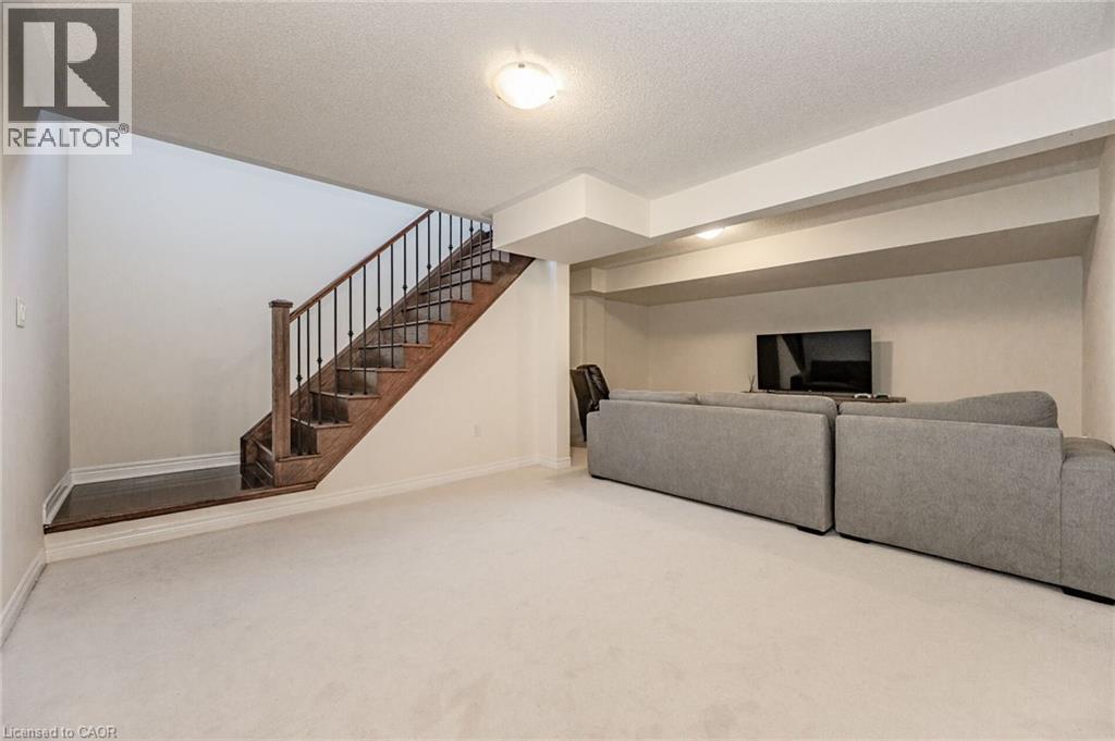 Recreation area featuring light-colored carpeting, a wooden staircase with black metal balusters, and recessed lighting - 2453 Village Common, Oakville, ON - Indoor