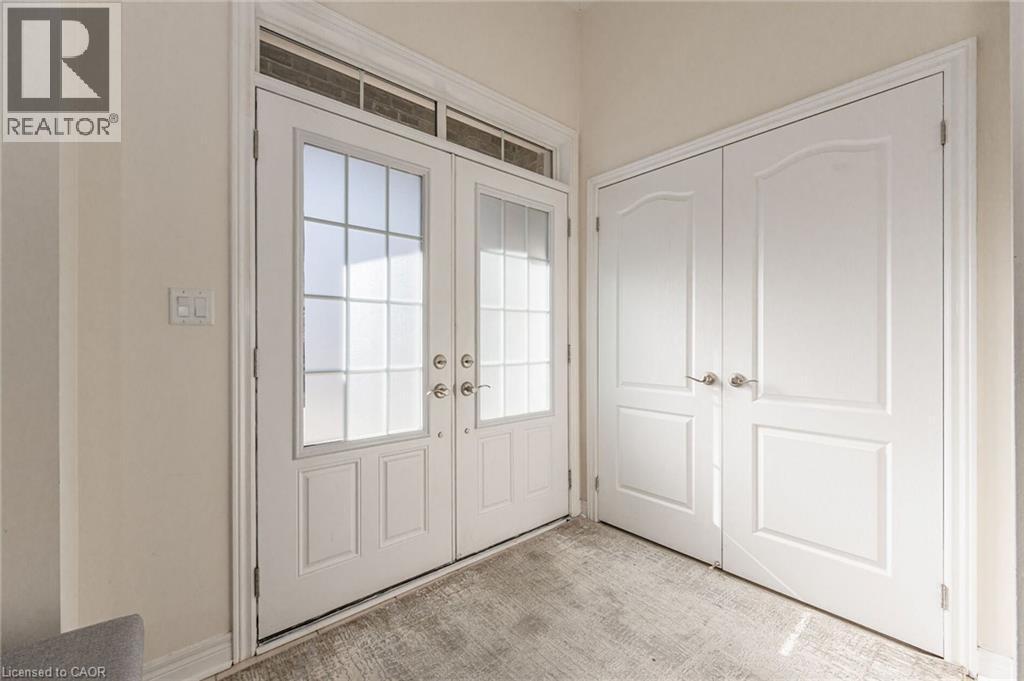The entryway features double doors with frosted glass panels and an overhead transom window, complemented by a pair of solid white doors with arched paneling - 2453 Village Common, Oakville, ON - Indoor Photo Showing Other Room
