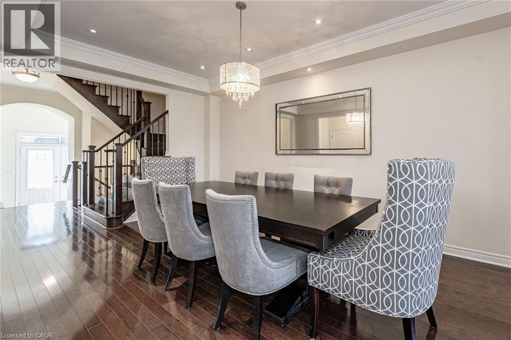 Formal dining area featuring hardwood floors, a dark wood dining table, and a tiered crystal chandelier - 2453 Village Common, Oakville, ON - Indoor Photo Showing Dining Room