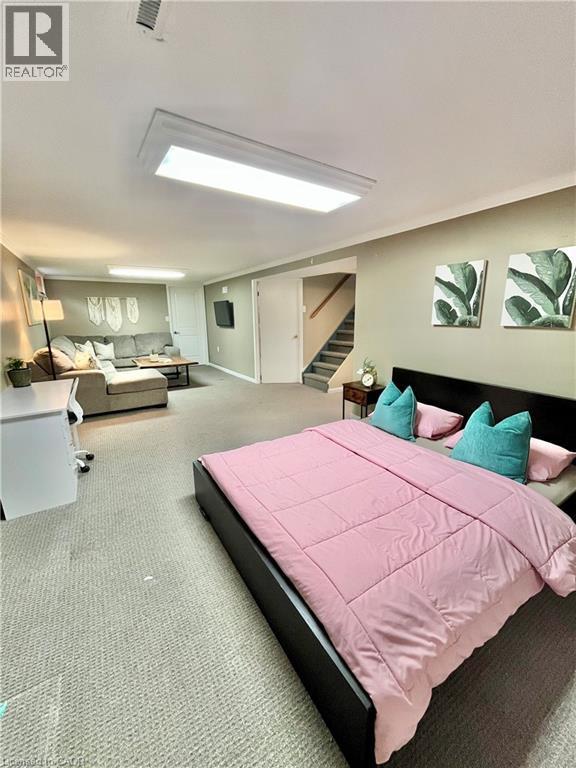 This versatile space features carpeting, a bed, and a staircase - 241 Thorner Drive, Hamilton, ON - Indoor Photo Showing Bedroom