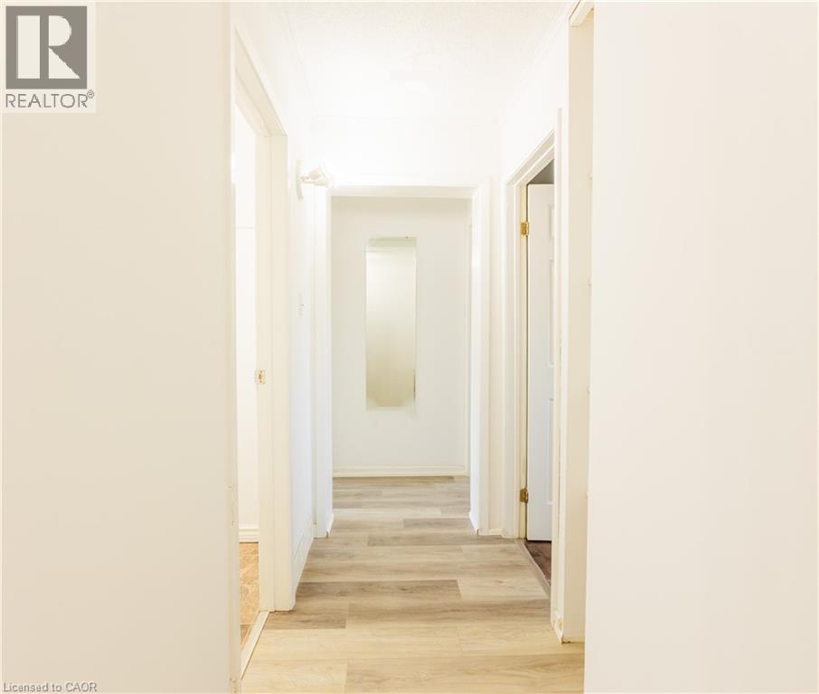 Hallway featuring light-toned flooring, white walls, and a recessed mirror - 121 University Avenue E Unit# 102, Waterloo, ON - Indoor Photo Showing Other Room