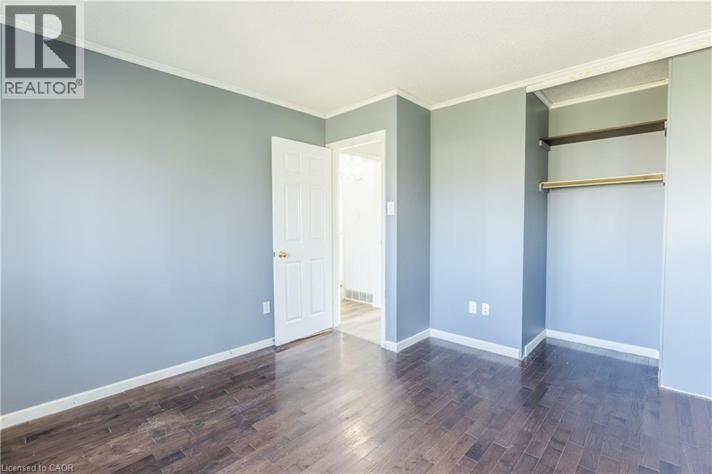 This room features dark hardwood flooring, light blue walls, and a white ceiling with crown molding - 121 University Avenue E Unit# 102, Waterloo, ON - Indoor Photo Showing Other Room