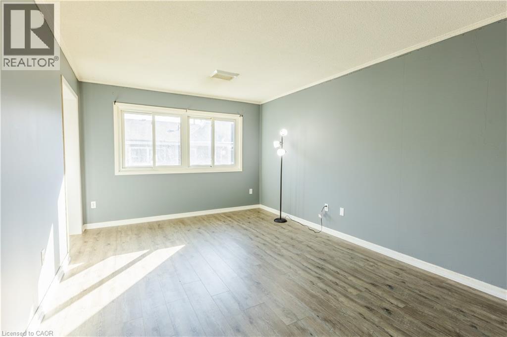 This room features light-colored flooring, windows providing natural light, and light blue walls with white trim - 121 University Avenue E Unit# 102, Waterloo, ON - Indoor Photo Showing Other Room