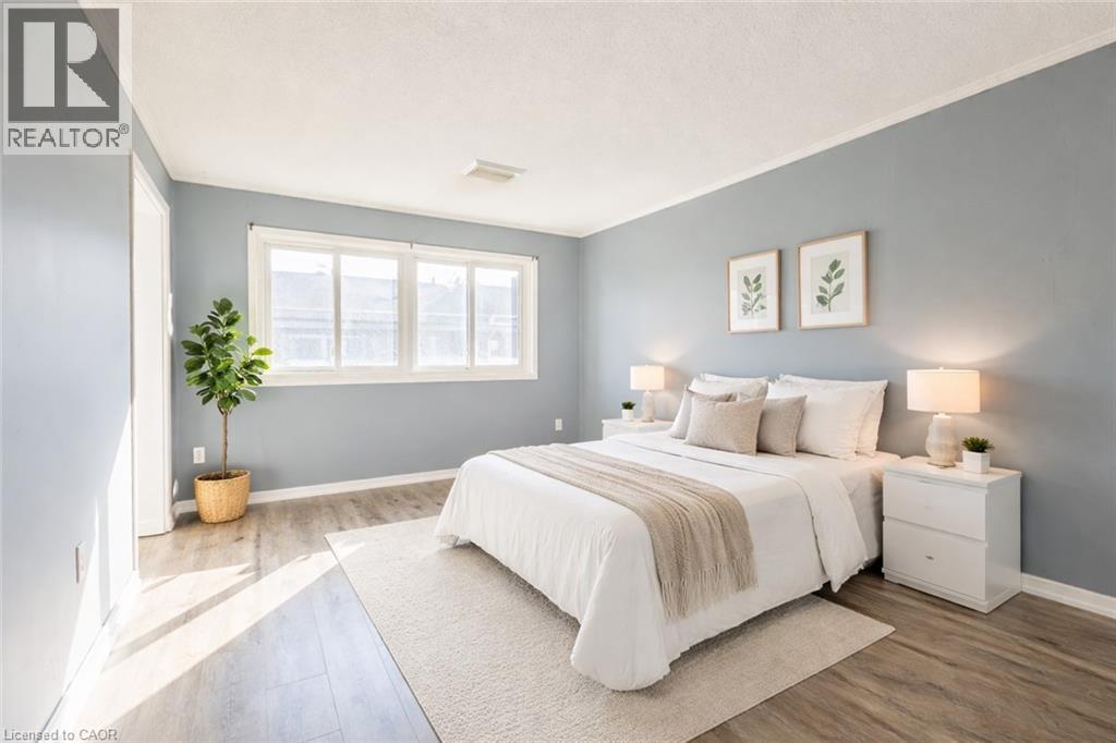 This room features light-colored walls, wood-style flooring, and a large window - 121 University Avenue E Unit# 102, Waterloo, ON - Indoor Photo Showing Bedroom