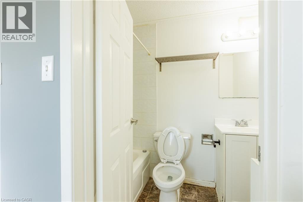 Bathroom featuring a vanity with a sink, a toilet, and a bathtub with tiled walls - 121 University Avenue E Unit# 102, Waterloo, ON - Indoor Photo Showing Bathroom