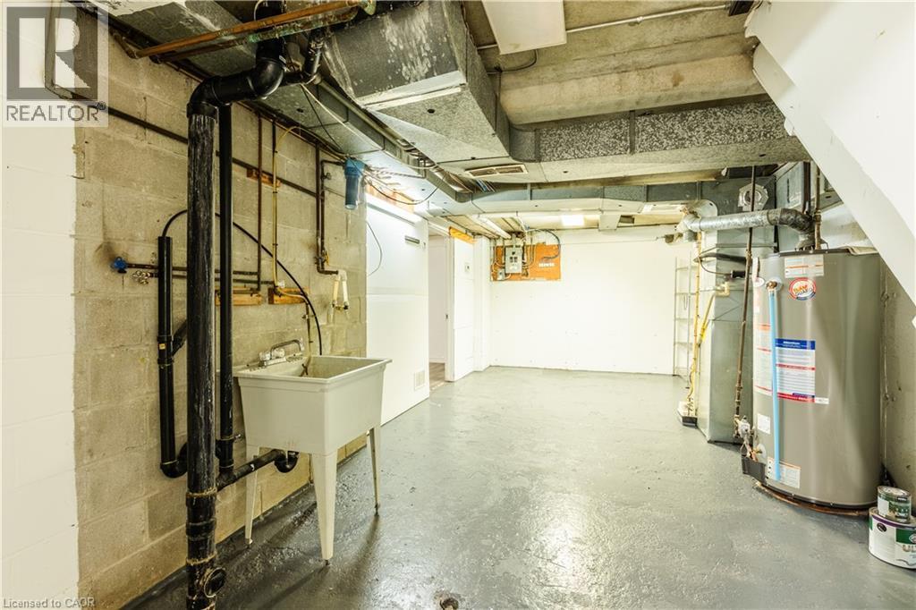 The property features a utility sink and a water heater, with exposed ductwork and piping - 121 University Avenue E Unit# 102, Waterloo, ON - Indoor Photo Showing Basement