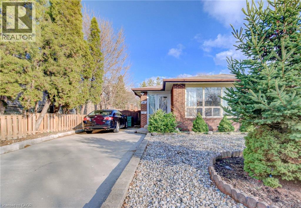 The property features a brick exterior, large front windows, and an extensive driveway - 141 Mooregate Crescent, Kitchener, ON - Outdoor