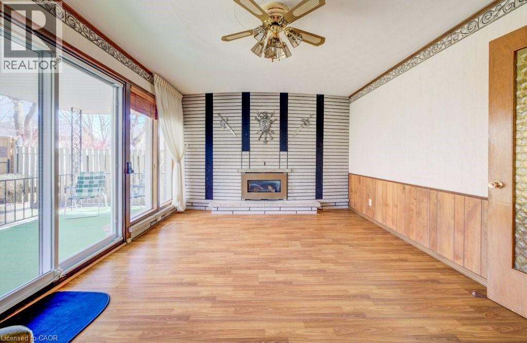 The family room with large windows and sliding door to your back yard oasis. Gas fireplace and a ceiling fan - 564 Glen Manor Boulevard, Waterloo, ON - Indoor Photo Showing Other Room With Fireplace