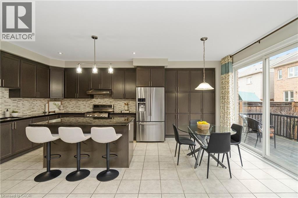 The kitchen features dark cabinetry, stainless steel appliances, and a tiled backsplash - 4 Macbean Crescent, Waterdown, ON - Indoor