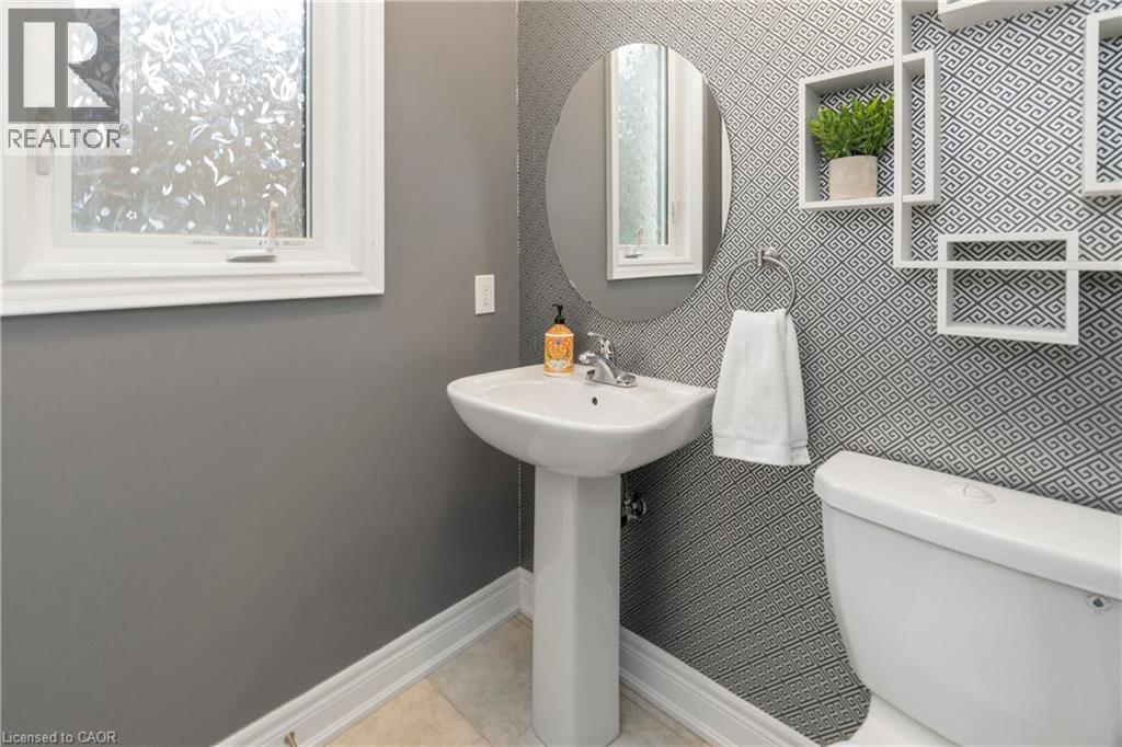 Bathroom featuring a pedestal sink, an oval mirror, and patterned wallpaper - 4 Macbean Crescent, Waterdown, ON - Indoor Photo Showing Bathroom