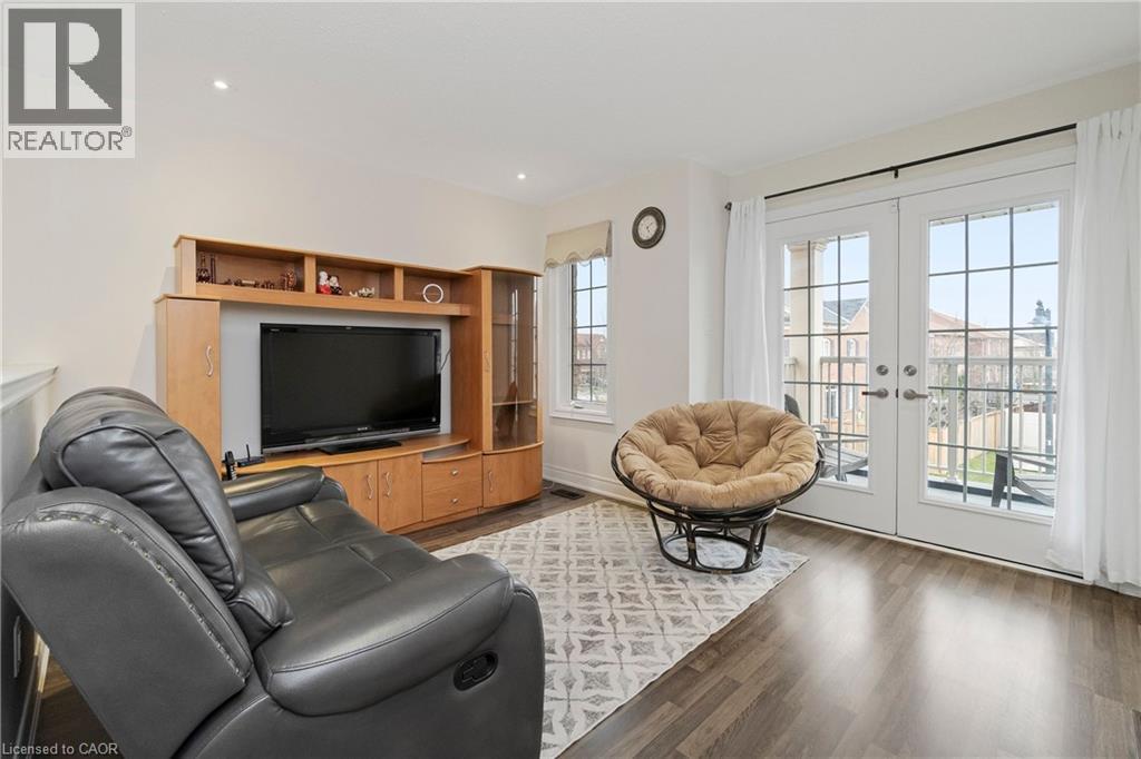 The property features laminate floors, light-colored walls, and a window with white curtains - 4 Macbean Crescent, Waterdown, ON - Indoor Photo Showing Living Room