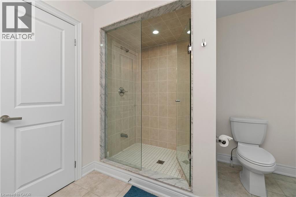 The bathroom features a glass-enclosed shower with tiled walls and a white tiled floor, alongside a white toilet - 4 Macbean Crescent, Waterdown, ON - Indoor Photo Showing Bathroom