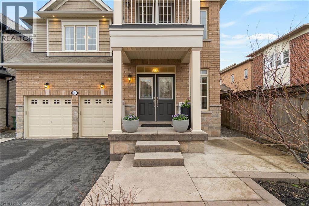 This property features a brick exterior with stone accents, a covered front porch with pillars, and a double car garage with individual doors - 4 Macbean Crescent, Waterdown, ON - Outdoor With Balcony With Facade