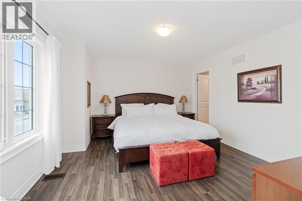 This room features wood -style flooring and a large window with white trim - 4 Macbean Crescent, Waterdown, ON - Indoor Photo Showing Bedroom