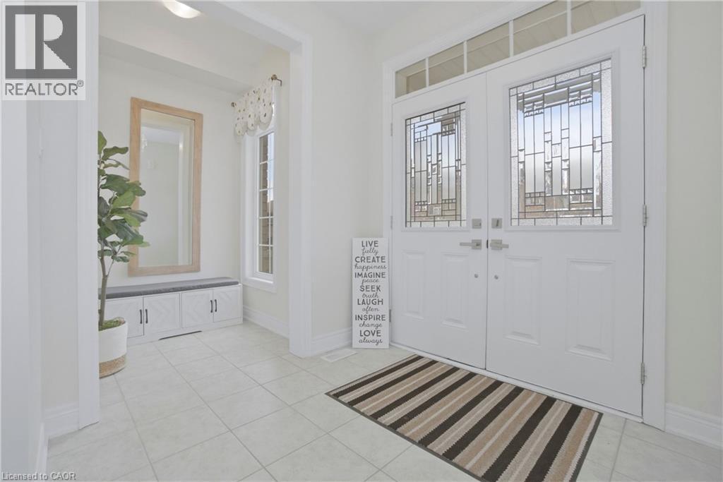 Inviting entry featuring a double front door with decorative glass inserts and an overhead transom window, tiled flooring, and a recessed area with a built-in bench and mirror - 4 Macbean Crescent, Waterdown, ON - Indoor Photo Showing Other Room