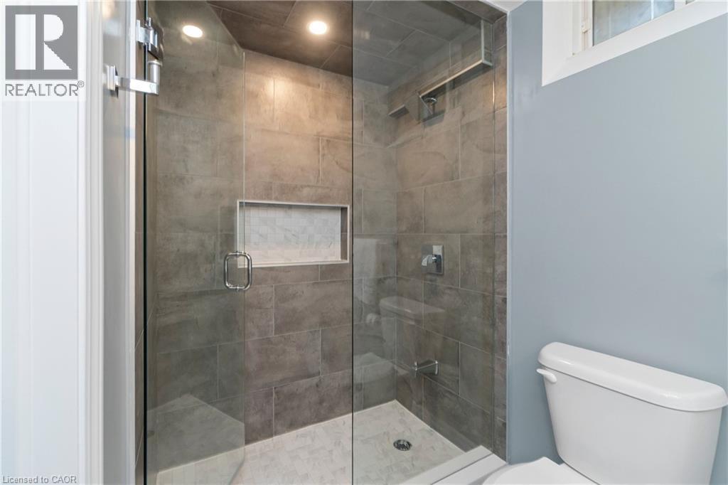 The bathroom features a spacious glass-enclosed shower with large format tile walls and a built-in niche - 4 Macbean Crescent, Waterdown, ON - Indoor Photo Showing Bathroom