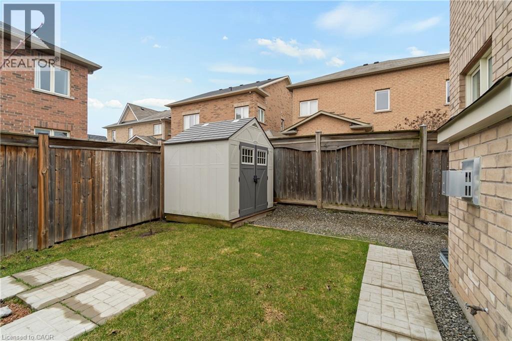 The property features a fenced yard with a lawn, a paved stone pathway, and a storage shed - 4 Macbean Crescent, Waterdown, ON - Outdoor With Exterior