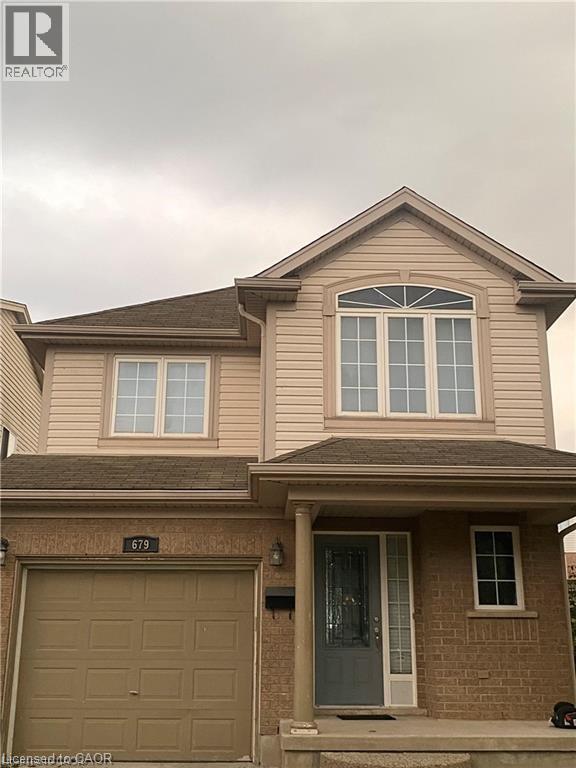 The property features a brick and siding exterior, an integrated garage, and a covered porch entrance - 679 Commonwealth Crescent Unit# Lower, Kitchener, ON - Outdoor With Exterior