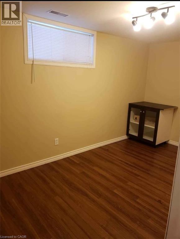 This room features rich brown flooring, a window with blinds, and track lighting - 679 Commonwealth Crescent Unit# Lower, Kitchener, ON - Indoor Photo Showing Other Room