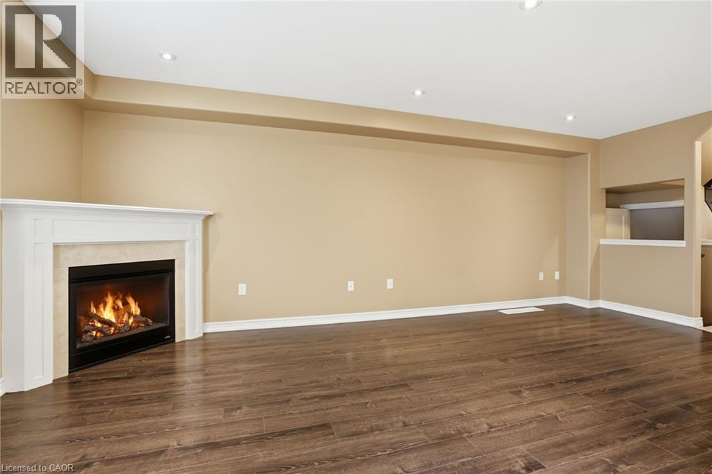 Unfurnished living room featuring dark wood-style flooring, recessed lighting, and a fireplace - 91 Chamomile Drive, Hamilton, ON - Indoor With Fireplace