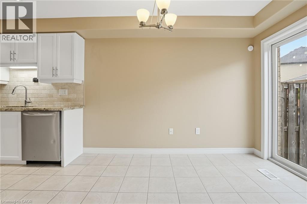 Kitchen featuring white cabinets, light stone counters, dishwasher, and tasteful backsplash - 91 Chamomile Drive, Hamilton, ON - Indoor Photo Showing Kitchen