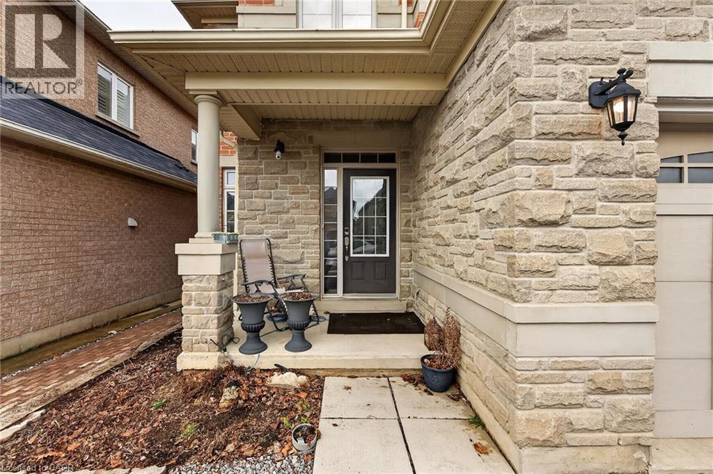 The property features an inviting front entrance with stone cladding, a covered porch with a column, and a concrete pathway - 44 Matteo Trail, Hamilton, ON - Outdoor With Exterior