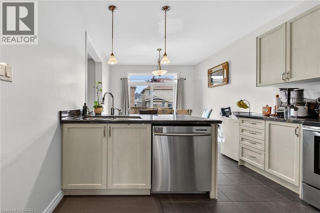 The kitchen features light-colored cabinetry, dark countertops, a stainless steel dishwasher, and tile flooring - 44 Matteo Trail, Hamilton, ON - Indoor Photo Showing Kitchen With Upgraded Kitchen