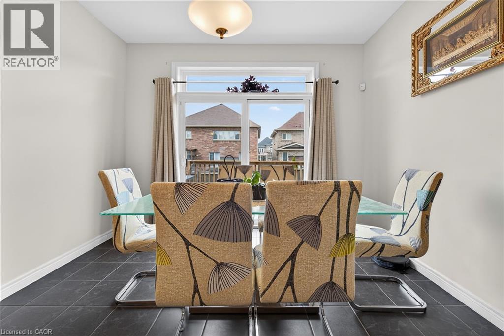 This dining area features neutral-toned walls and dark floor tiles - 44 Matteo Trail, Hamilton, ON - Indoor Photo Showing Dining Room