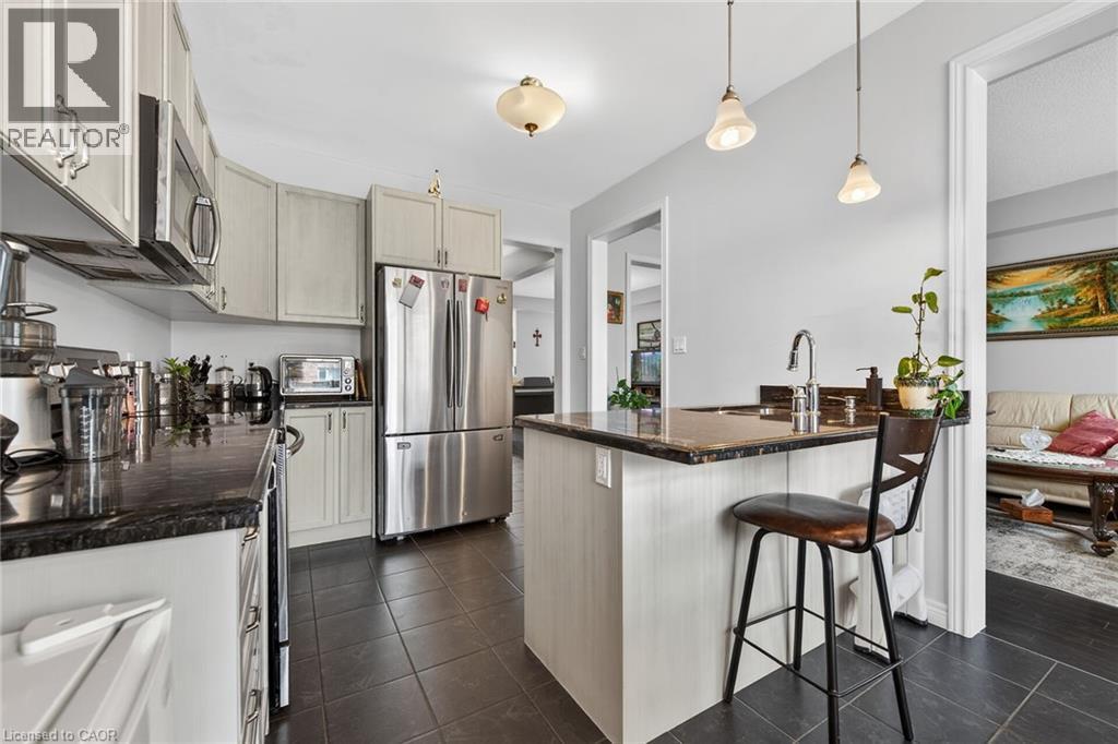 Kitchen featuring dark tile flooring, light-colored cabinetry with stainless steel hardware, and dark countertops - 44 Matteo Trail, Hamilton, ON - Indoor Photo Showing Kitchen With Upgraded Kitchen