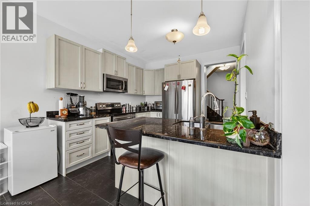 The kitchen features light-colored cabinetry, dark countertops, and stainless steel appliances - 44 Matteo Trail, Hamilton, ON - Indoor Photo Showing Kitchen