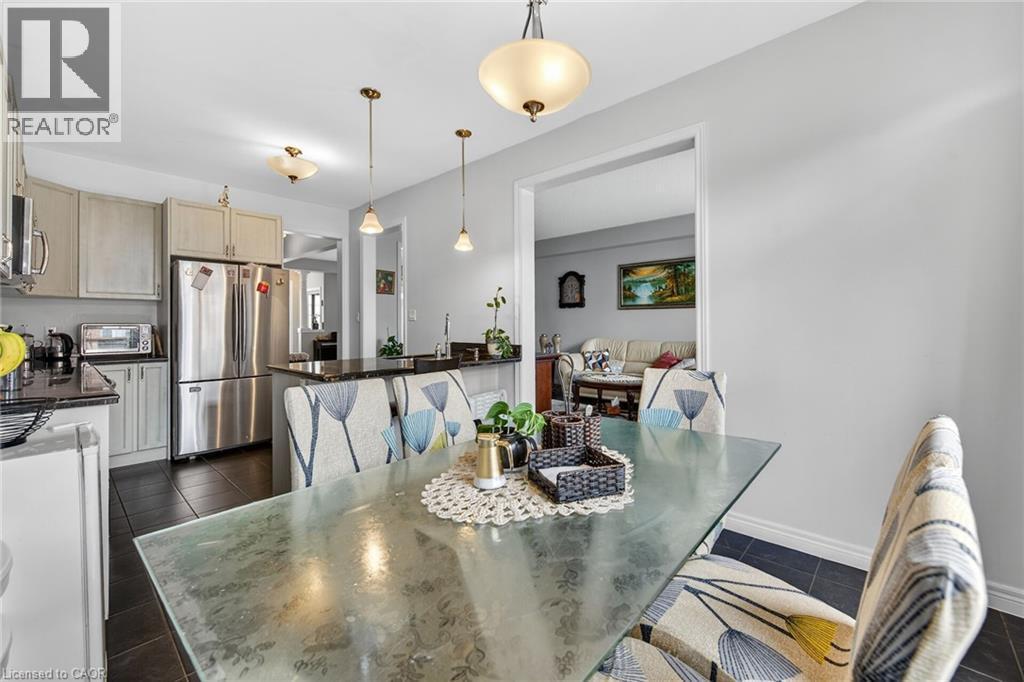 The kitchen features light-colored cabinetry, stainless steel appliances, and dark countertops - 44 Matteo Trail, Hamilton, ON - Indoor