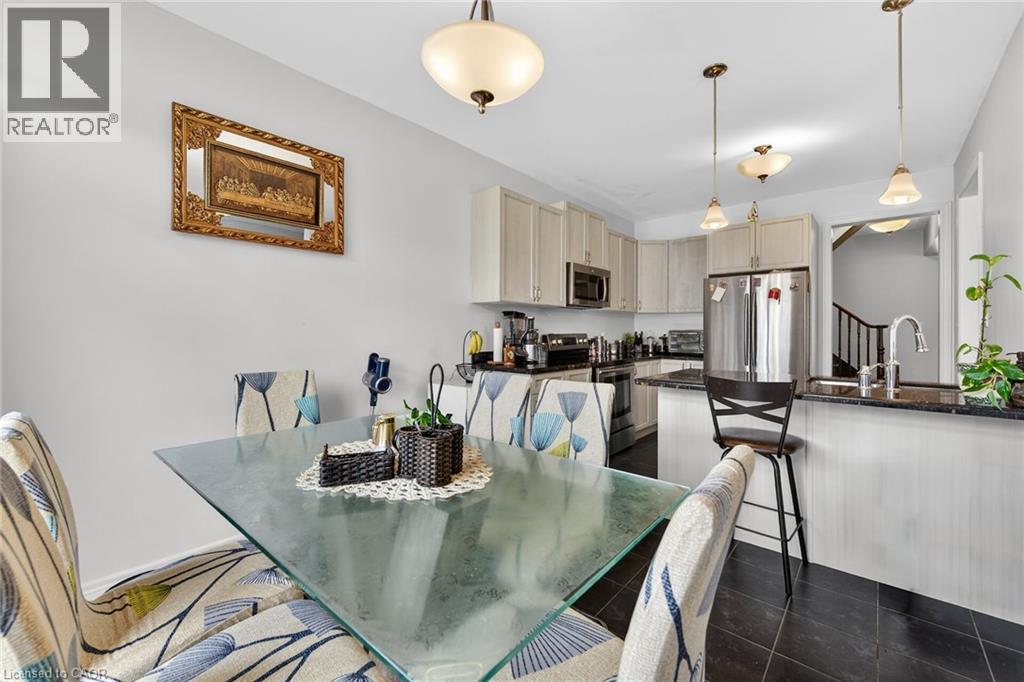 Open concept kitchen featuring dark tiled flooring, light-colored cabinetry, stainless steel appliances, and dark countertops - 44 Matteo Trail, Hamilton, ON - Indoor Photo Showing Dining Room