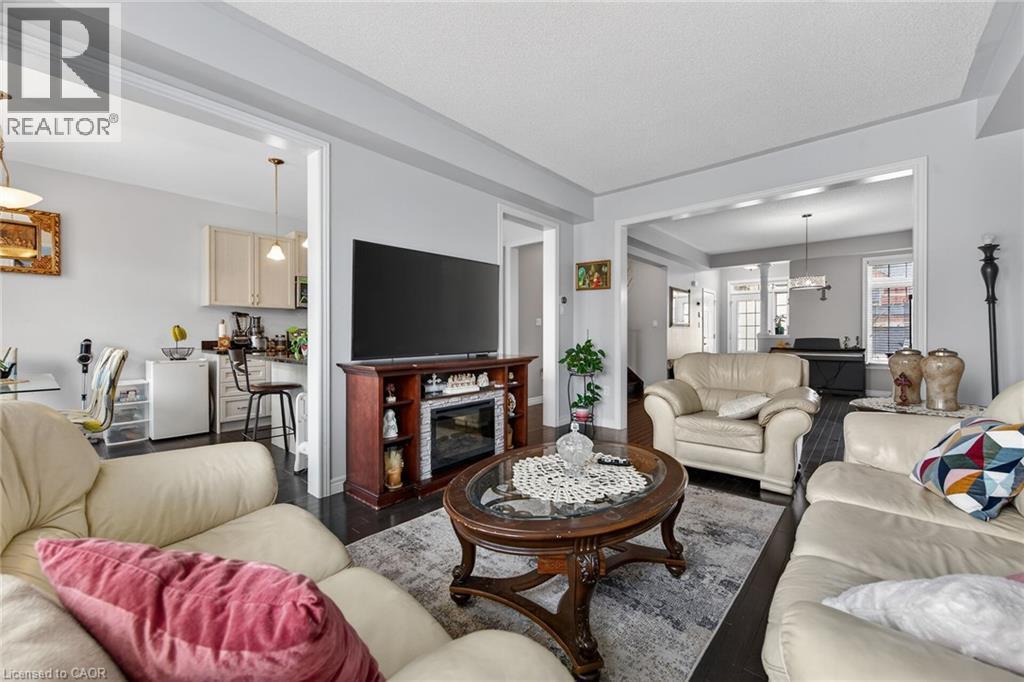 The living area features dark flooring, light-colored walls, and a decorative fireplace with a mantel - 44 Matteo Trail, Hamilton, ON - Indoor Photo Showing Living Room