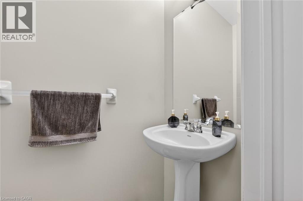 Bathroom featuring a pedestal sink with a chrome faucet and a wall-mounted mirror - 44 Matteo Trail, Hamilton, ON - Indoor Photo Showing Bathroom