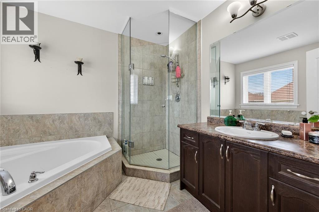 Bathroom featuring a large corner tub, a glass-enclosed shower, a vanity with a built-in sink, and a window with blinds - 44 Matteo Trail, Hamilton, ON - Indoor Photo Showing Bathroom