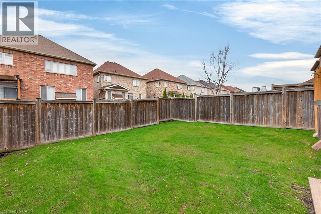 The property features a spacious backyard with a well-maintained lawn and a tall wooden fence providing privacy - 44 Matteo Trail, Hamilton, ON - Outdoor