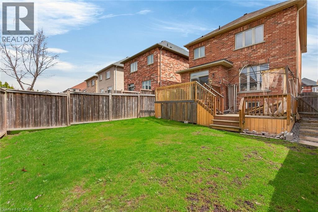 The property features a brick exterior and a wooden deck with stairs leading down to a fenced yard - 44 Matteo Trail, Hamilton, ON - Outdoor With Deck Patio Veranda
