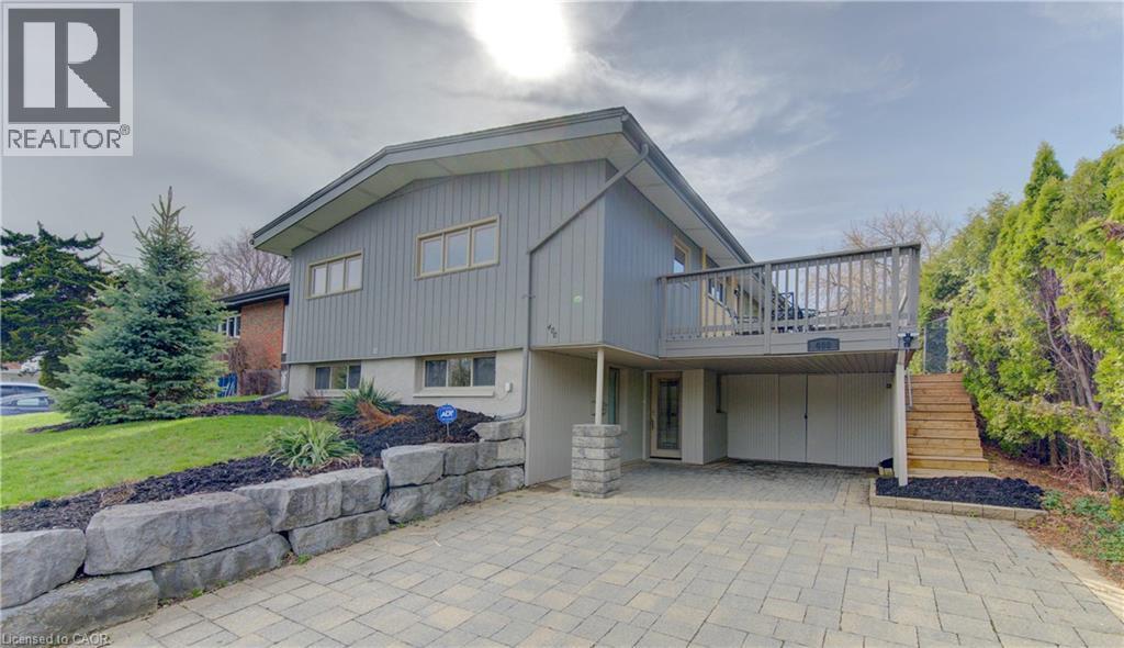 The property features a split-level design with light gray siding and a gray wood deck - 400 Manchester Road, Kitchener, ON - Outdoor With Deck Patio Veranda