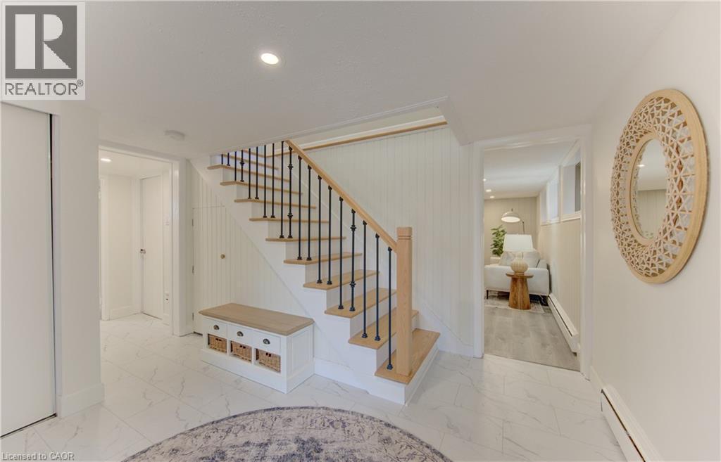 This property features a bright staircase with natural wood treads and handrail, complemented by black iron balusters - 400 Manchester Road, Kitchener, ON - Indoor Photo Showing Other Room