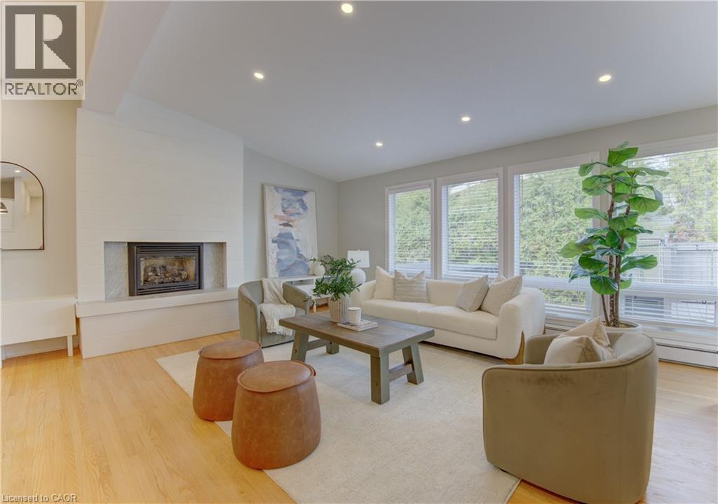 The property features an inviting living room with hardwood floors, a white brick fireplace, and recessed lighting - 400 Manchester Road, Kitchener, ON - Indoor Photo Showing Living Room With Fireplace
