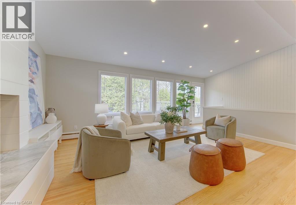 The living area features hardwood floors, a light-colored area rug, recessed lighting, and a white fireplace with a light-colored marble hearth - 400 Manchester Road, Kitchener, ON - Indoor Photo Showing Other Room