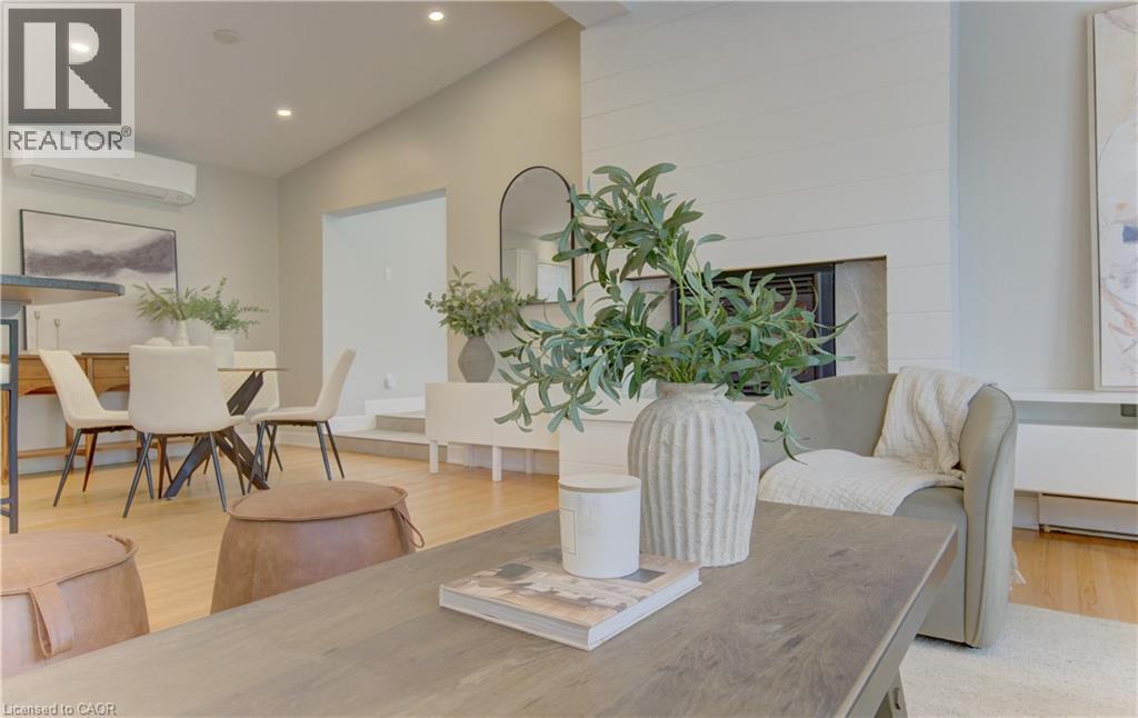 The property features an open-concept living area with light-colored hardwood floors, recessed lighting, and a fireplace with a white shiplap-style surround - 400 Manchester Road, Kitchener, ON - Indoor Photo Showing Dining Room