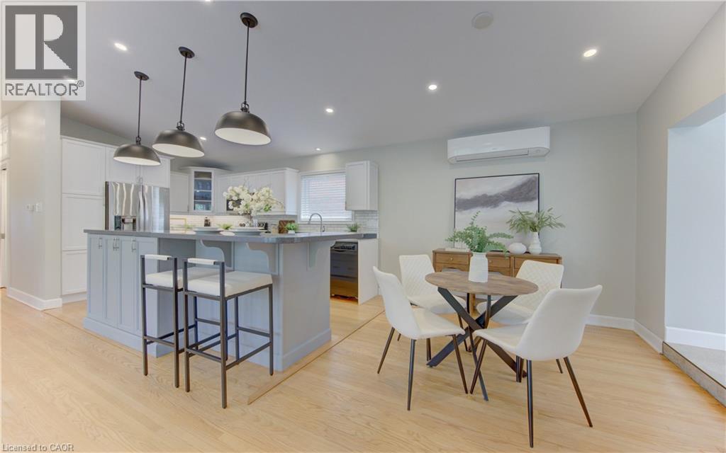 Kitchen and dining area featuring light wood flooring, an island with pendant lighting, white cabinetry, and stainless steel appliances - 400 Manchester Road, Kitchener, ON - Indoor Photo Showing Dining Room