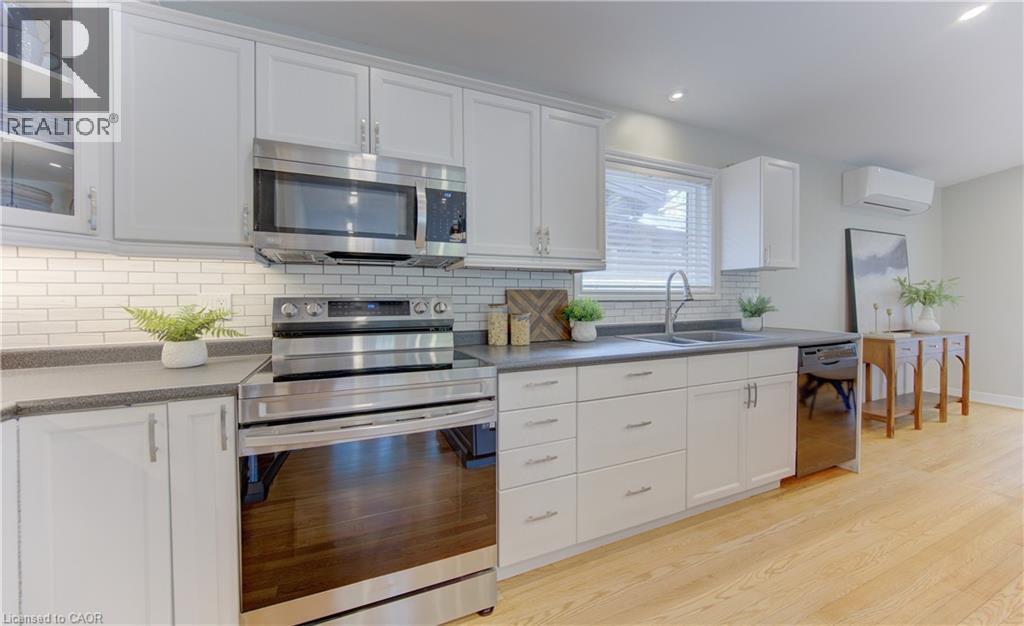 The kitchen features white cabinetry, stainless steel appliances, and a subway tile backsplash - 400 Manchester Road, Kitchener, ON - Indoor Photo Showing Kitchen With Double Sink