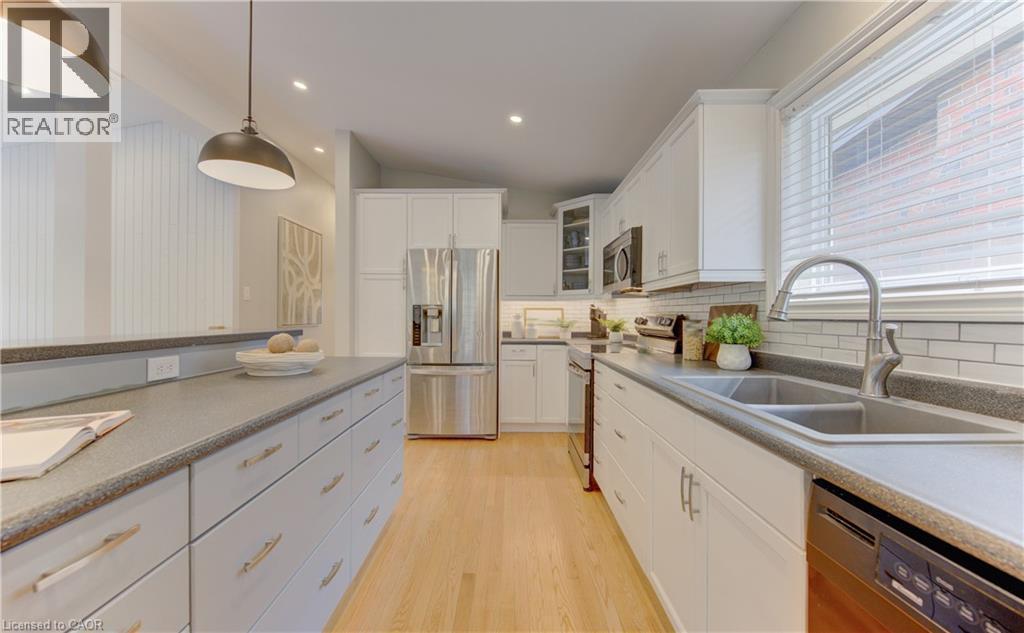 The kitchen features light wood flooring, white cabinetry, a double basin sink, and stainless steel appliances including a refrigerator and dishwasher - 400 Manchester Road, Kitchener, ON - Indoor Photo Showing Kitchen With Double Sink With Upgraded Kitchen