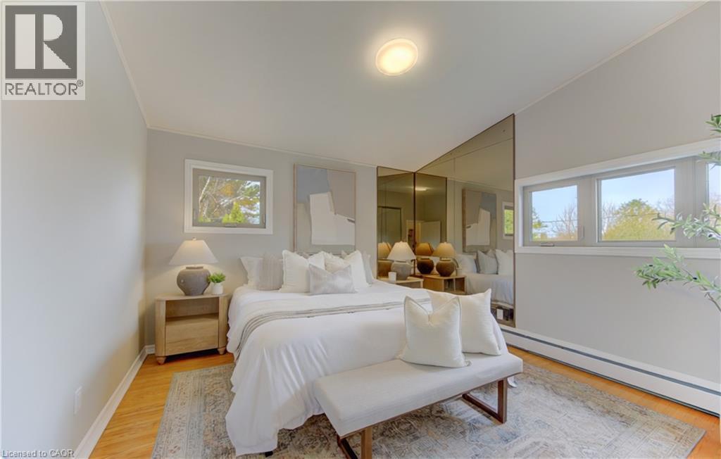 This inviting room features warm wood flooring, ample natural light from multiple windows, and a vaulted ceiling - 400 Manchester Road, Kitchener, ON - Indoor Photo Showing Bedroom