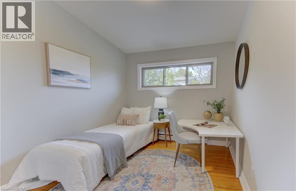 This room features light-colored walls, wood flooring, and a large window providing natural light - 400 Manchester Road, Kitchener, ON - Indoor Photo Showing Bedroom