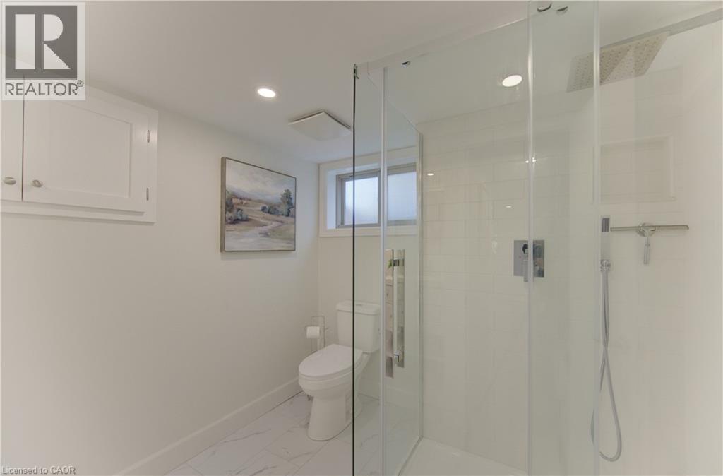 The bathroom features a glass-enclosed shower with a rain shower head and a handheld shower, a toilet, and recessed lighting - 400 Manchester Road, Kitchener, ON - Indoor Photo Showing Bathroom