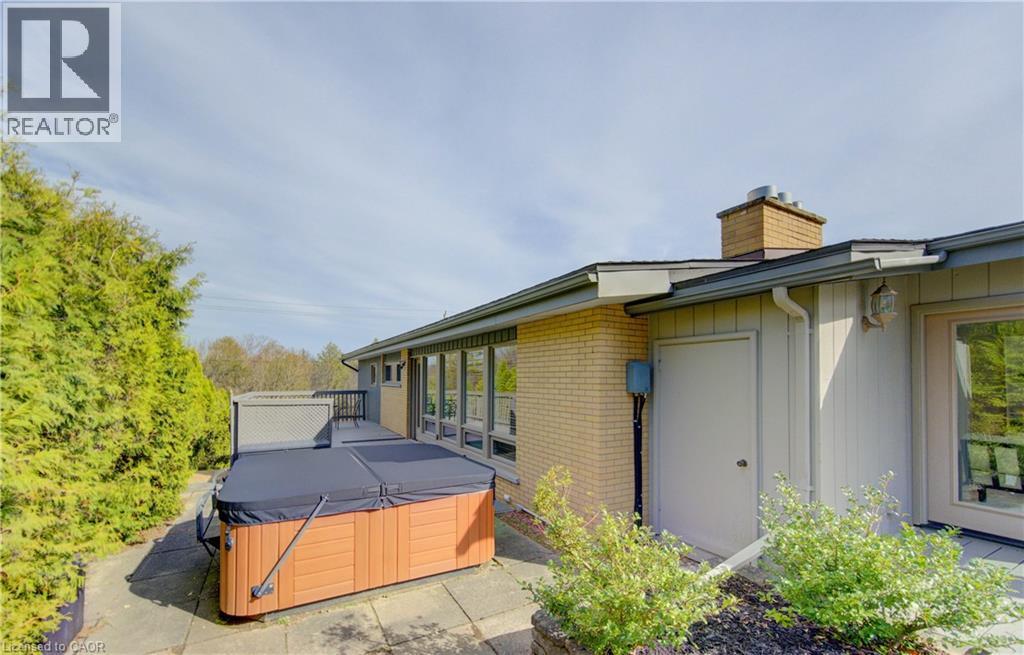The exterior of the property features a light brick facade and a multi-level deck, with a hot tub on the lower level - 400 Manchester Road, Kitchener, ON - Outdoor With Exterior