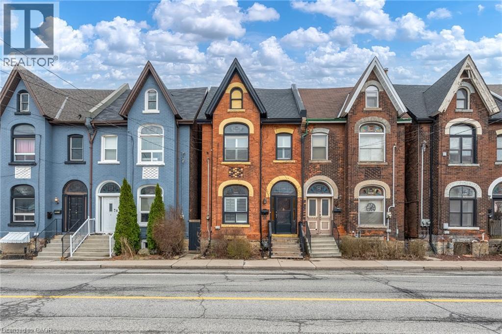 This property features a brick facade with arched windows and doors, and a pitched roof - 198 Bay Street N, Hamilton, ON - Outdoor With Facade